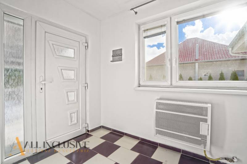 A hallway in a family house with white doors, a window, and tiles.