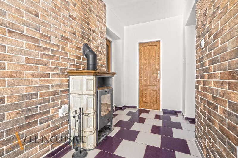 Interior of a family house with a tiled stove and brick walls.