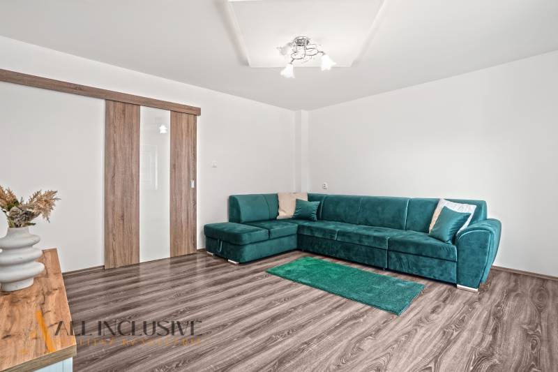 Living room in a family house with a sofa and wood-patterned flooring.