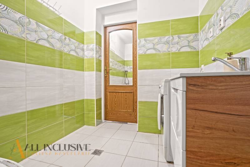 A bathroom in a family house with colorful tiles, wooden doors, and a washing machine.
