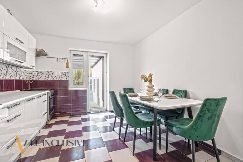 A kitchen with a dining table, colorful floor, and an exit to the terrace in a family house.