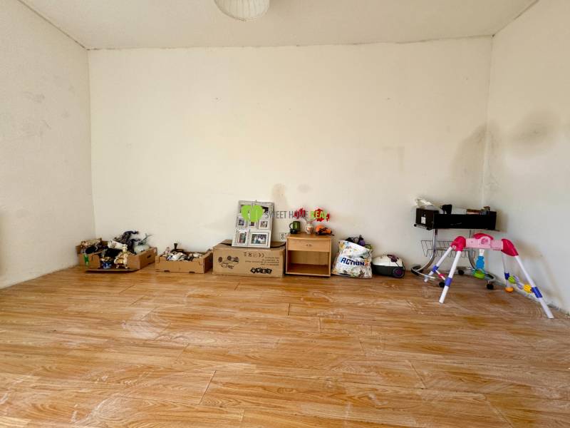 A room in a family house with walls covered in toys and a floor with a wooden decor.