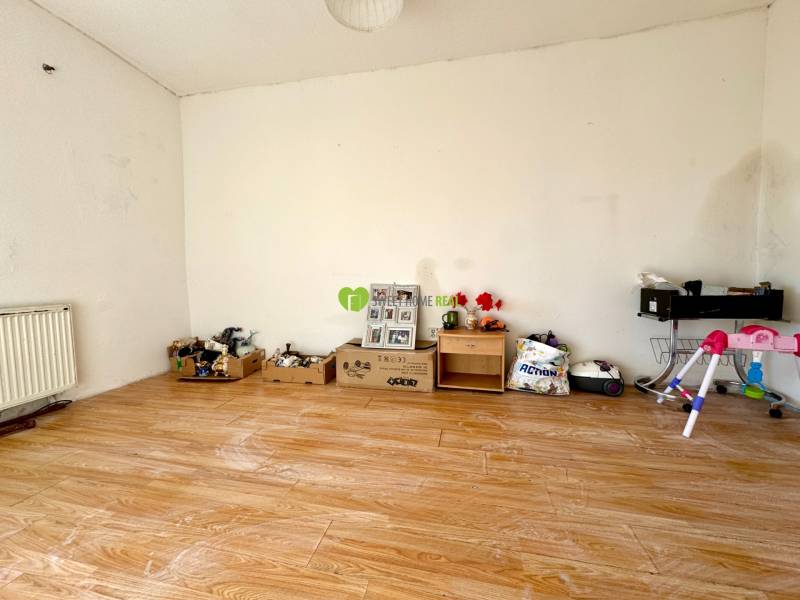 A room in a family house with a wooden decor floor and various objects by the wall.