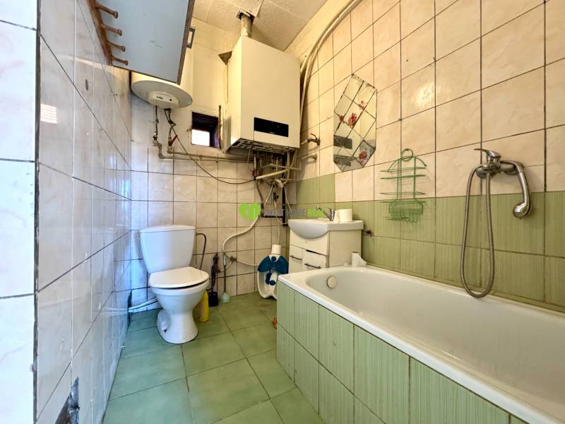 A bathroom in a family house with a bathtub, sink, toilet, and tiles with a color contrast.
