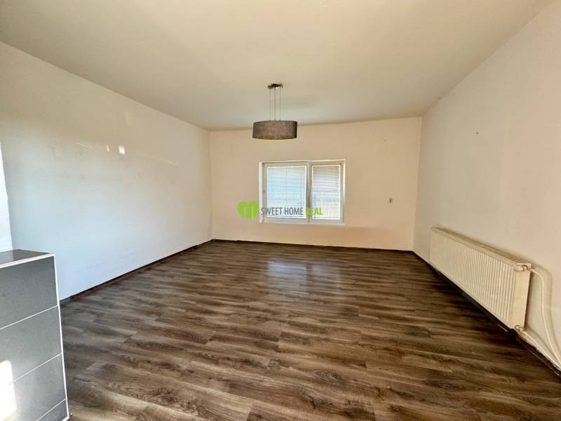 Living room with wood-patterned flooring and a radiator in a family house.