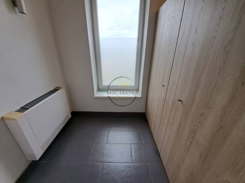 Office with tiles, storage space, and a large window, without furniture.