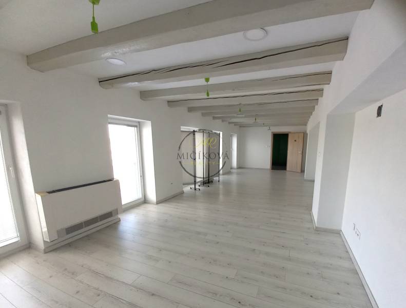 White office with wood-patterned flooring, decorative beams, and light-colored walls.