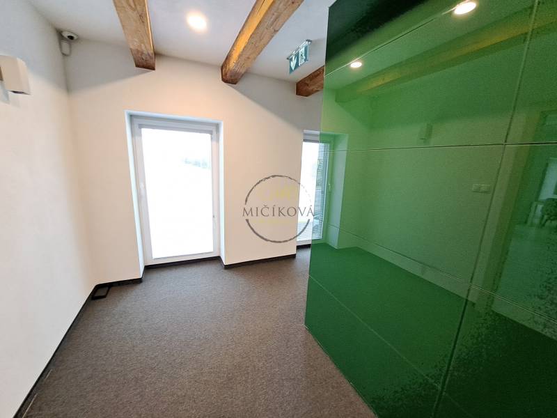 Office spaces with wooden beams and a green wall, carpeted floor.