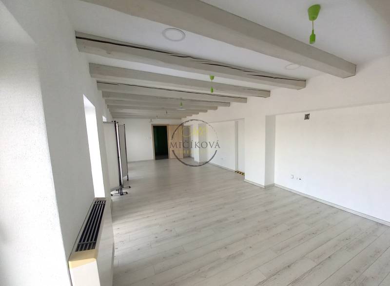 Empty office with white walls and wood-patterned flooring.