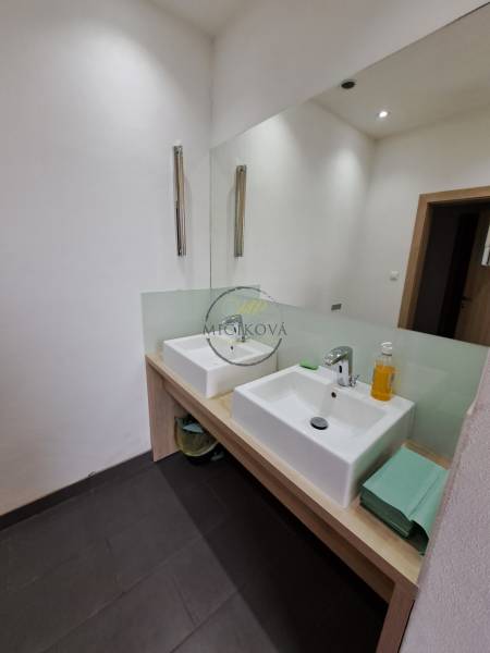 Double sink in the office bathroom with white walls and a large mirror.