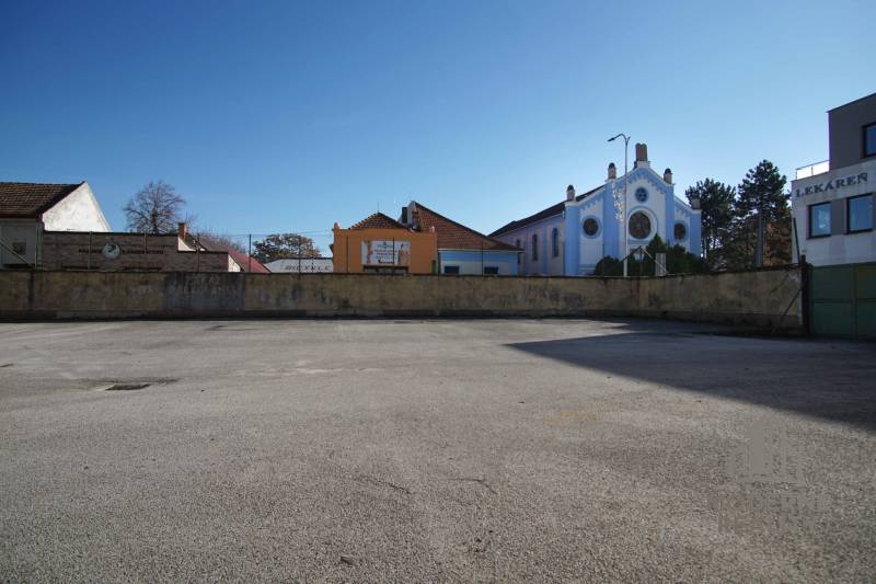 A vacant residential plot in Nové Zámky, surrounded by historical buildings and a pharmacy.