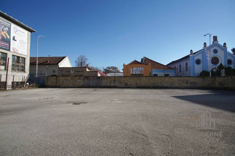 Urban space in Nové Zámky suitable for residential plots, surrounded by buildings and wooden houses.