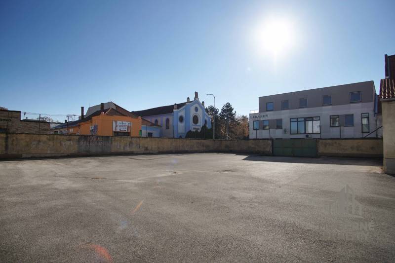 A plot in Nové Zámky suitable for living, surrounded by buildings and sunny weather.