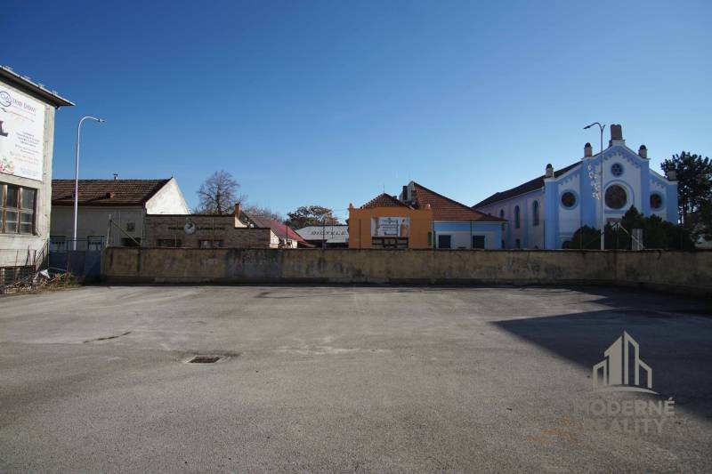 An empty asphalt space near a historic building in Nové Zámky, suitable for residential plots.