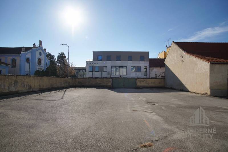 A plot in Nové Zámky suitable for living, surrounded by buildings, clean asphalt surfaces.