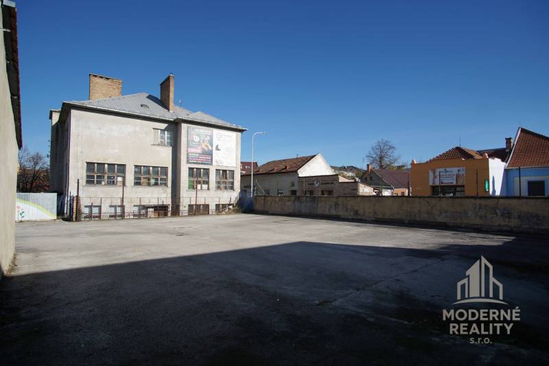 Exterior of buildings and open area in the town of Nové Zámky, suitable for residential land.