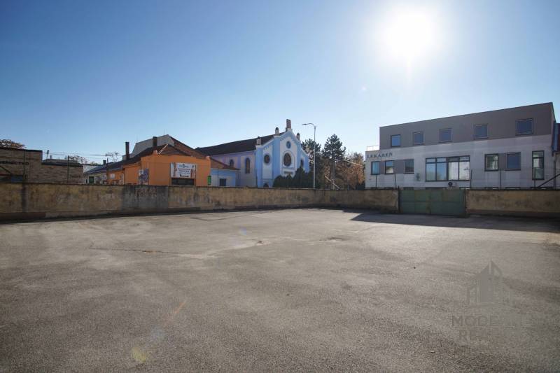 Photograph of a residential plot in Nové Zámky. The shot shows buildings in the background.