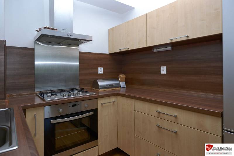 A kitchen in a 2-room apartment with a wood decor and a stainless steel range hood.
