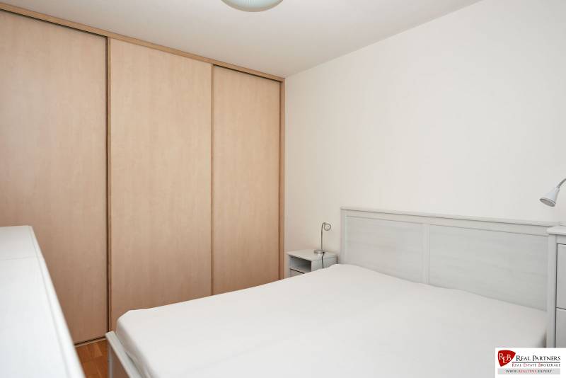 Bedroom in a 2-room apartment with a bed, wardrobe, and white walls.