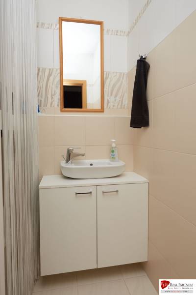 Bathroom with a mirror and a sink above a cabinet in a 2-room apartment.