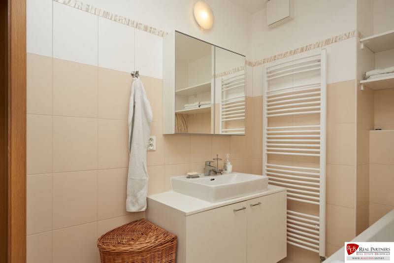 Bathroom in a 2-room apartment with white furniture, a mirror, and a towel.