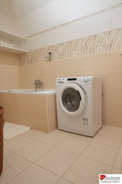 A bathroom with a bathtub, washing machine, and shelf in a 2-room apartment.