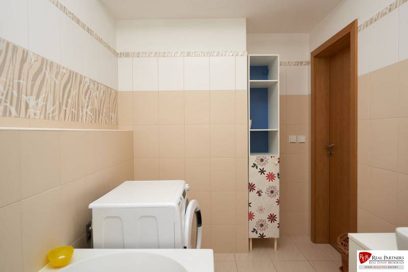 Bathroom with a washing machine, tiles with a plant pattern, cabinet with a floral motif, 2-room apartment.