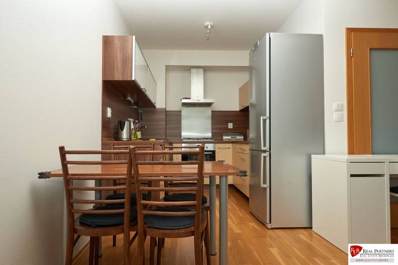 A kitchen in a 2-room apartment with a wooden decor floor and wooden furniture.