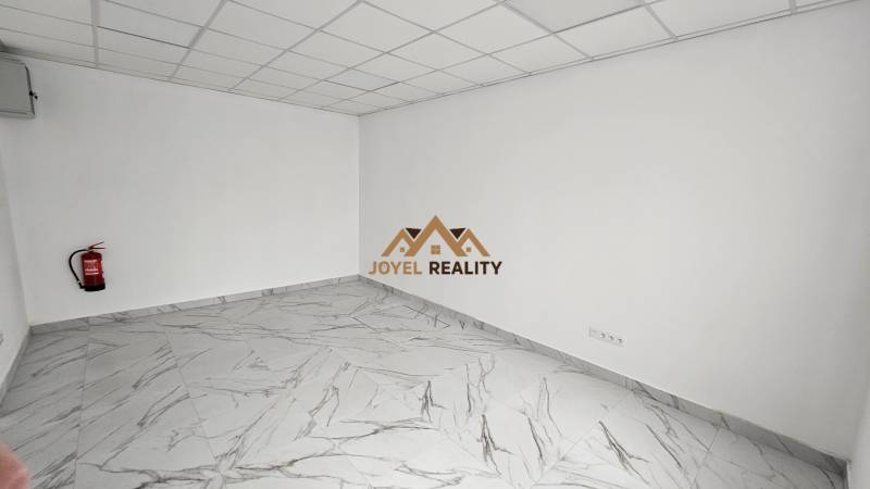 Commercial premises with a marble floor and a fire extinguisher by the wall.