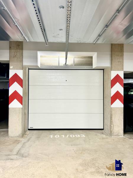 A closed garage on Karpatská Street in Poprad with white doors and a concrete floor.