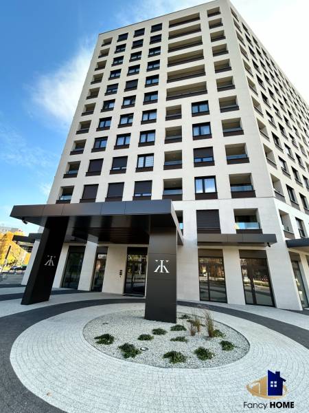 A high-rise building on Karpatská Street in Poprad with a modern entrance and curved walkways.