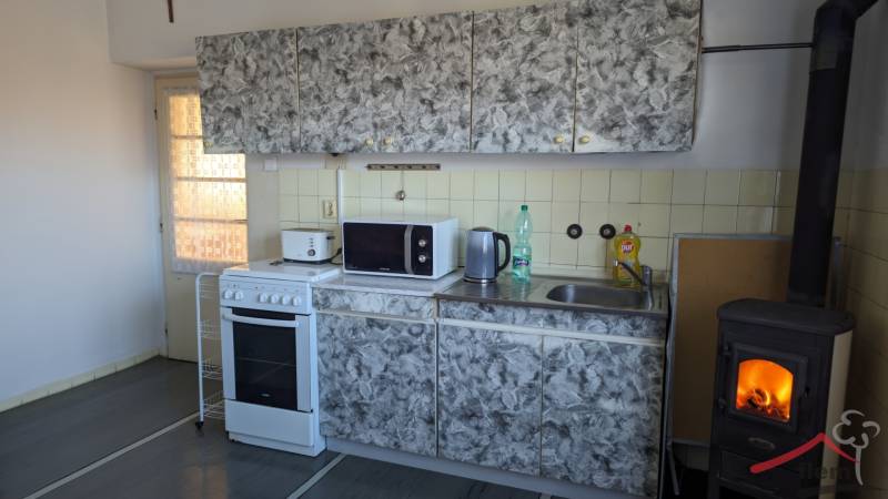 A kitchen with tiles, a stove, and a fireplace in a family house, with a wooden decor floor.