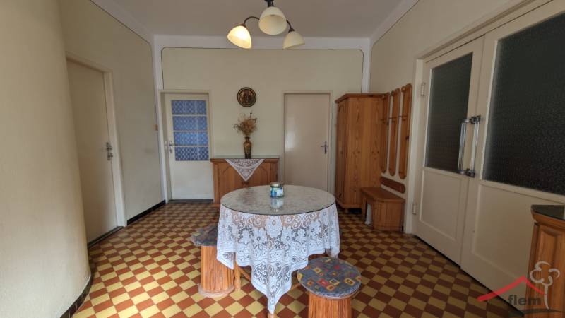 Dining room in a family house with a round table, patterned floor, and wooden furniture.