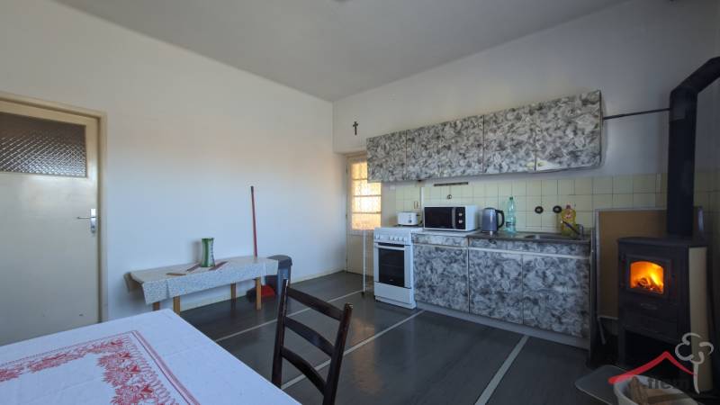 A kitchen in a family house with a stove and kitchen cabinets, floor with wooden decor.