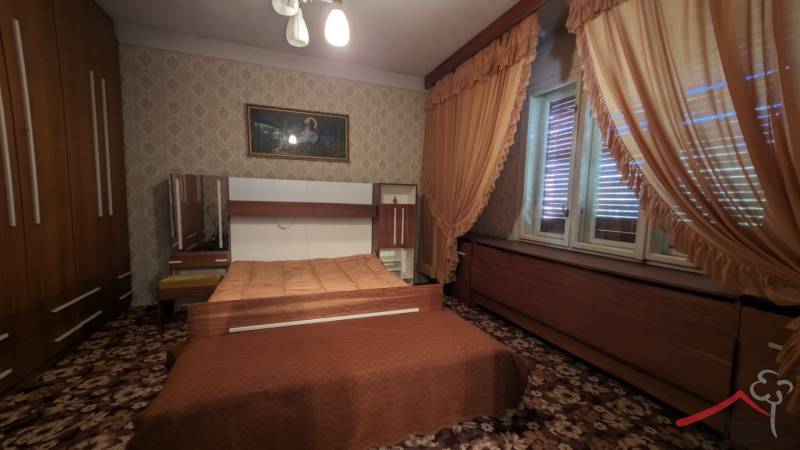 A bedroom in a family house with a carpet, furniture, and curtains in shades of brown.