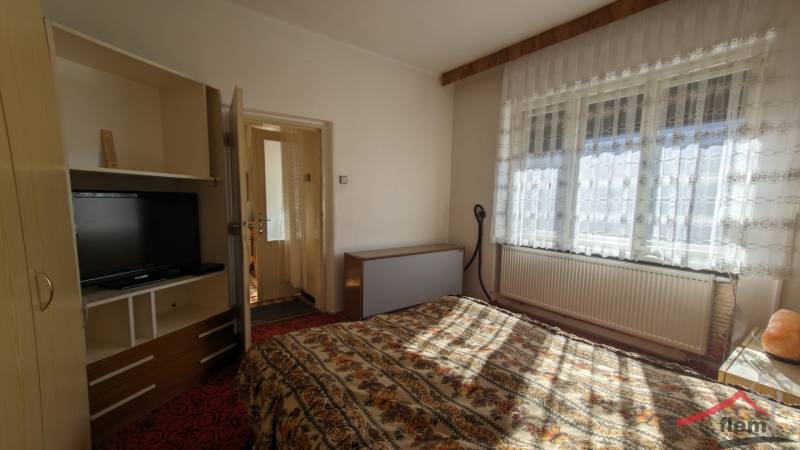 A bedroom in a family house with a television and floral patterned bed linen.