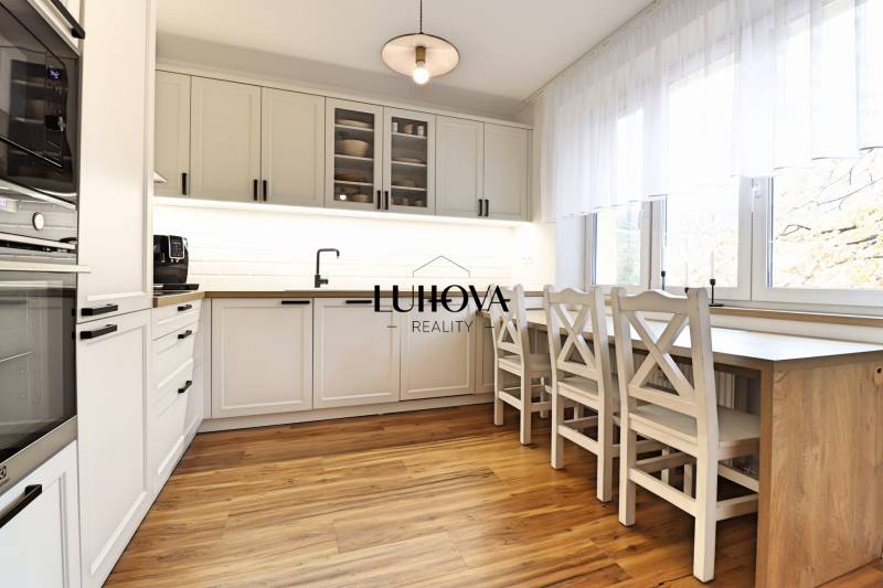 The kitchen in a 3-room apartment with white cabinets and a wood-patterned floor.