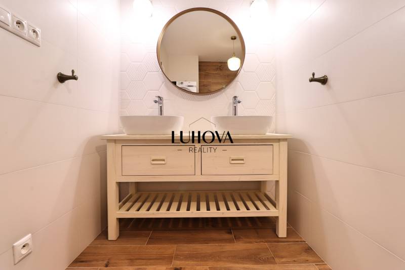 A bathroom in a 3-room apartment with a double sink and a wooden decor floor.