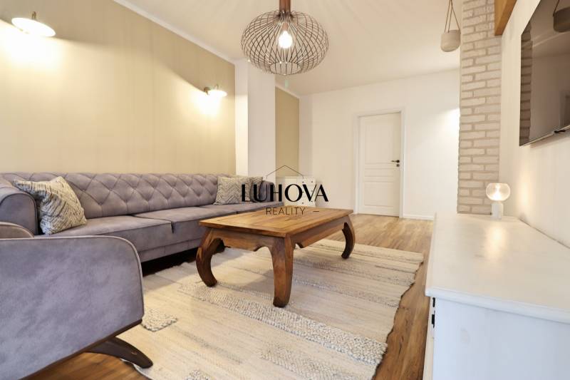 Living room in a 3-room apartment with a sofa, wooden table, and wooden decor flooring.