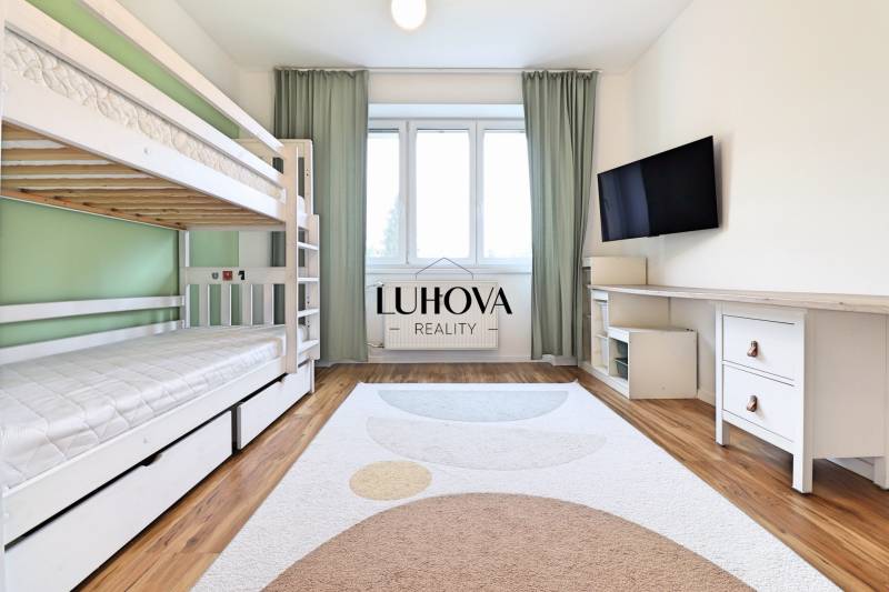 A room in a 3-room apartment with a bunk bed, a television, and a floor with a wooden decor.