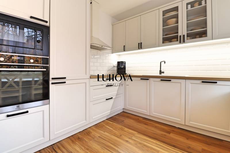 A kitchen in a 3-room apartment with white cabinets and a wooden decor floor.