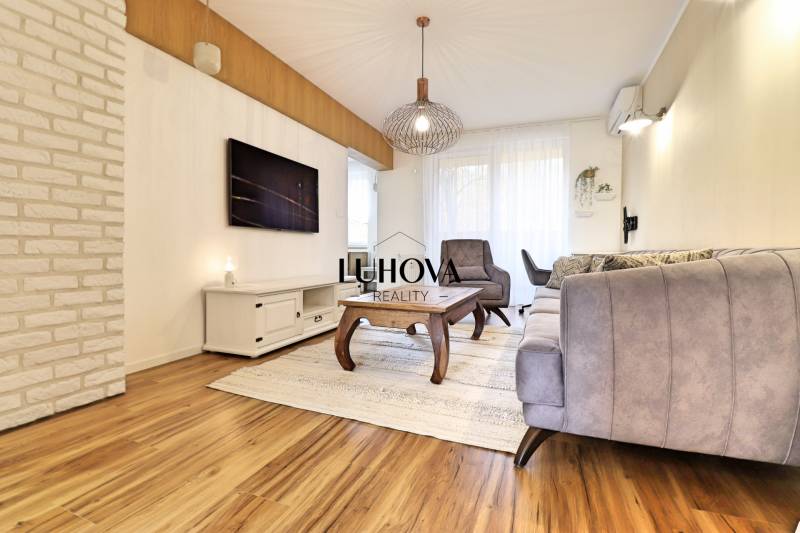 Living room with a sofa and an armchair in a 3-room apartment with a wooden decor floor.