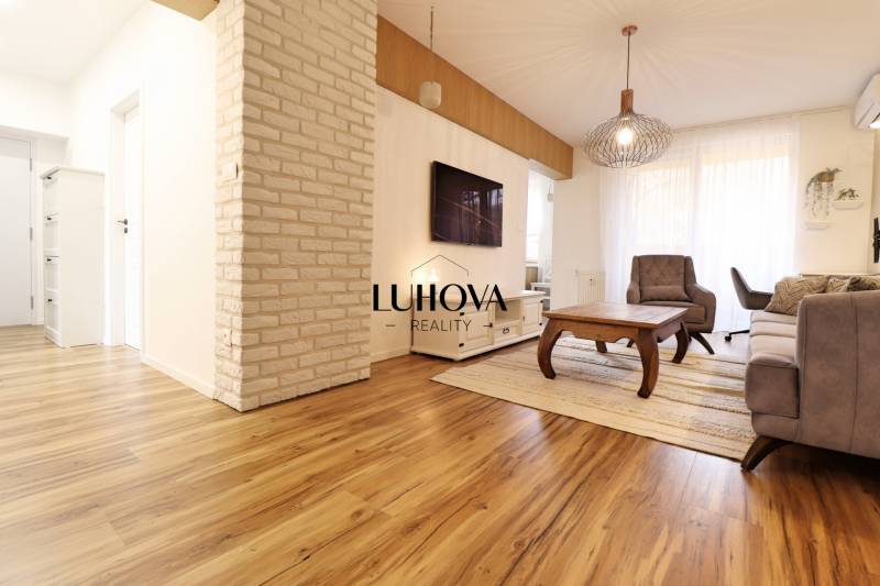 Living room in a three-room apartment with a wooden decor floor and brick cladding on the wall.