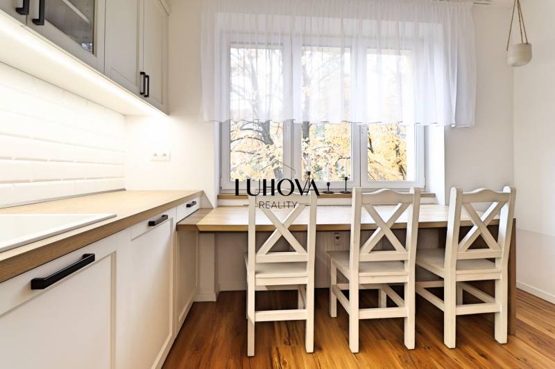 Dining area in the kitchen of a 3-room apartment, floor with wood decor, white cabinets.