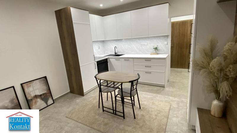 A kitchen in a studio apartment with white cabinets and a dining table.