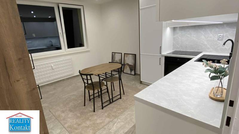 A kitchen in a studio apartment with a dining table, cabinets, and decorative paintings on the wall.