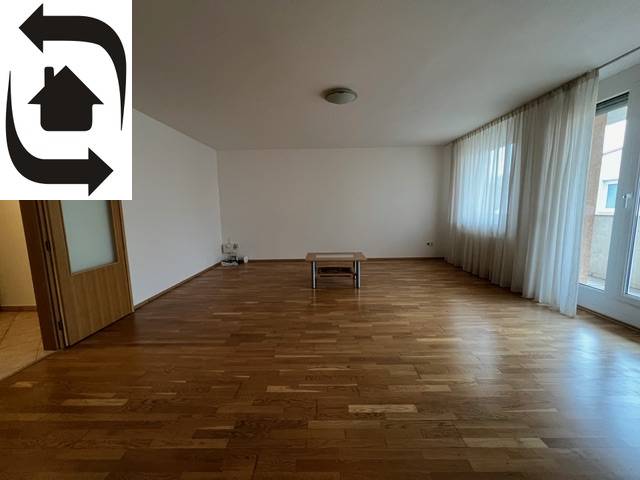 Spacious living room with wooden flooring and windows in a 3-room apartment.