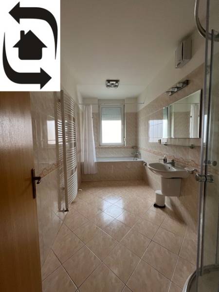 Bathroom in a 3-room apartment with a bathtub, glass shower enclosure, and light tiles.