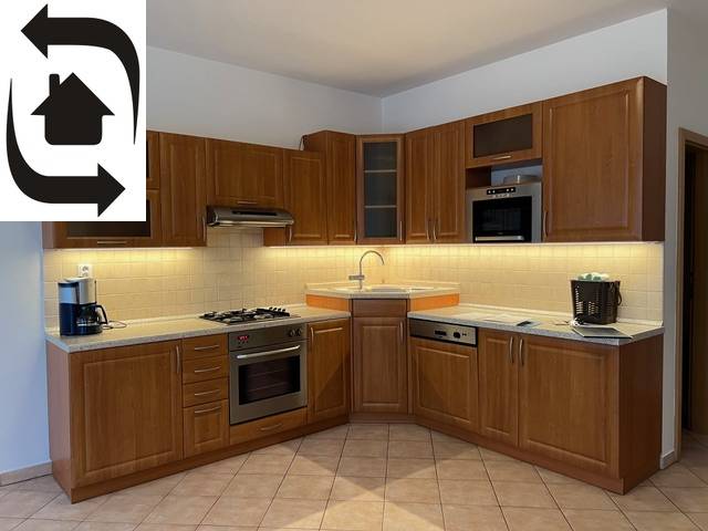 A kitchen unit in a 3-room apartment with wooden cabinets and appliances, light brown tiles.