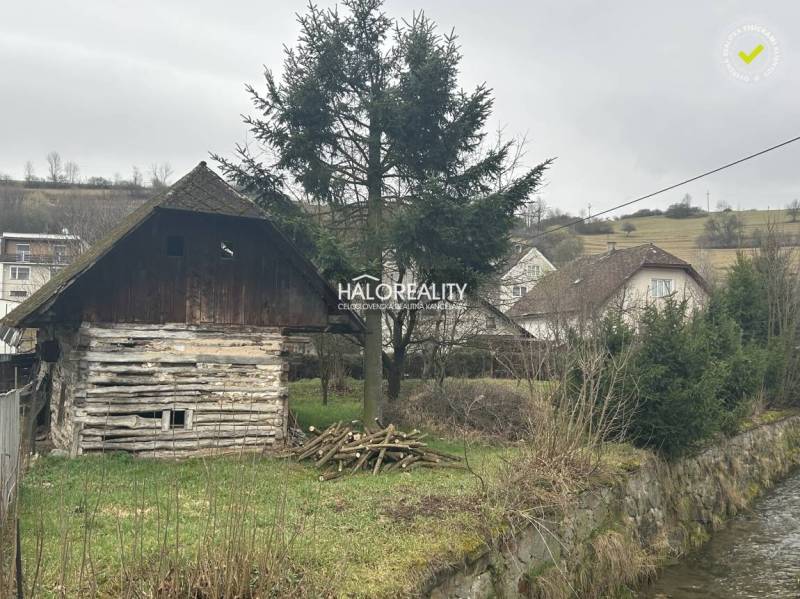 A wooden cottage by the stream, surrounded by trees, grass on the property - living in the countryside.